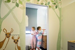 Een badkamer met een muurschildering van een boom, een handdoekhouder en een wastafel.