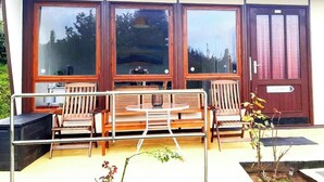 A modern building with large windows, a wooden bench, and a small table.