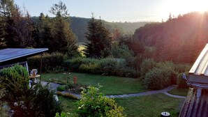 A garden with a lawn, a pathway, and a variety of plants and trees.