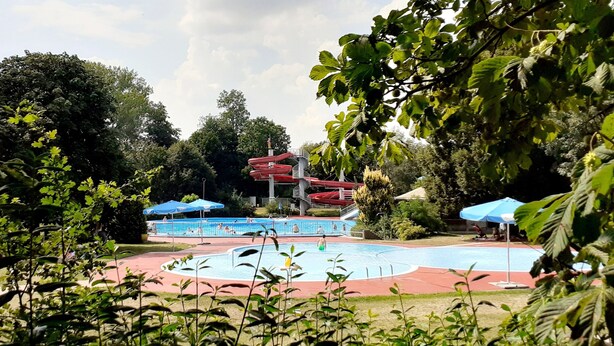 A swimming pool with a water slide and umbrellas.
