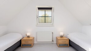 A bedroom with two single beds, a window, a radiator, and bedside tables with lamps. - Cosy Holiday Home in Twente (Hoge Hexel)