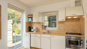 A compact kitchen with a dishwasher, a coffee maker, a stove, and a microwave. - Cosy Holiday Home in Twente (Hoge Hexel)