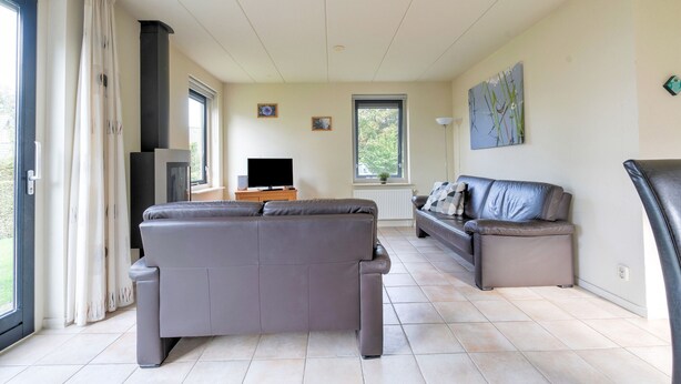 Ein Wohnzimmer mit einer grauen Couch, einer kleineren grauen Couch, einem Fernseher und einem Kamin.