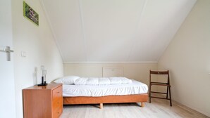 Ein Schlafzimmer mit einem hölzernen Bett, einer Holzkommode und einem Stuhl.