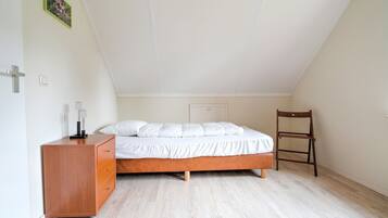 A bedroom with a wooden bed, a wooden dresser, and a chair.