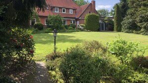 A house with a red-tiled roof, surrounded by a well-maintained lawn and various shrubs. - Vacation apartment "Zum Wiesenblick" in the heath village of Eimke, 130 sqm  (Eimke)