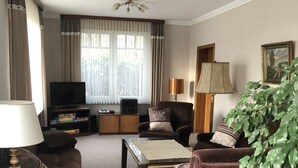 A living room with a sofa, armchair, coffee table, TV, and a bookshelf. - Vacation apartment "Zum Wiesenblick" in the heath village of Eimke, 130 sqm  (Eimke)