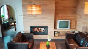 A modern living room with leather sofas, a wooden coffee table, a fireplace, and a television. - A Superb Cottage in the Middle of a Natural Park (Hotton)