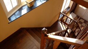 A staircase with a wooden handrail and a black carpeted landing area. - A Superb Cottage in the Middle of a Natural Park (Hotton)