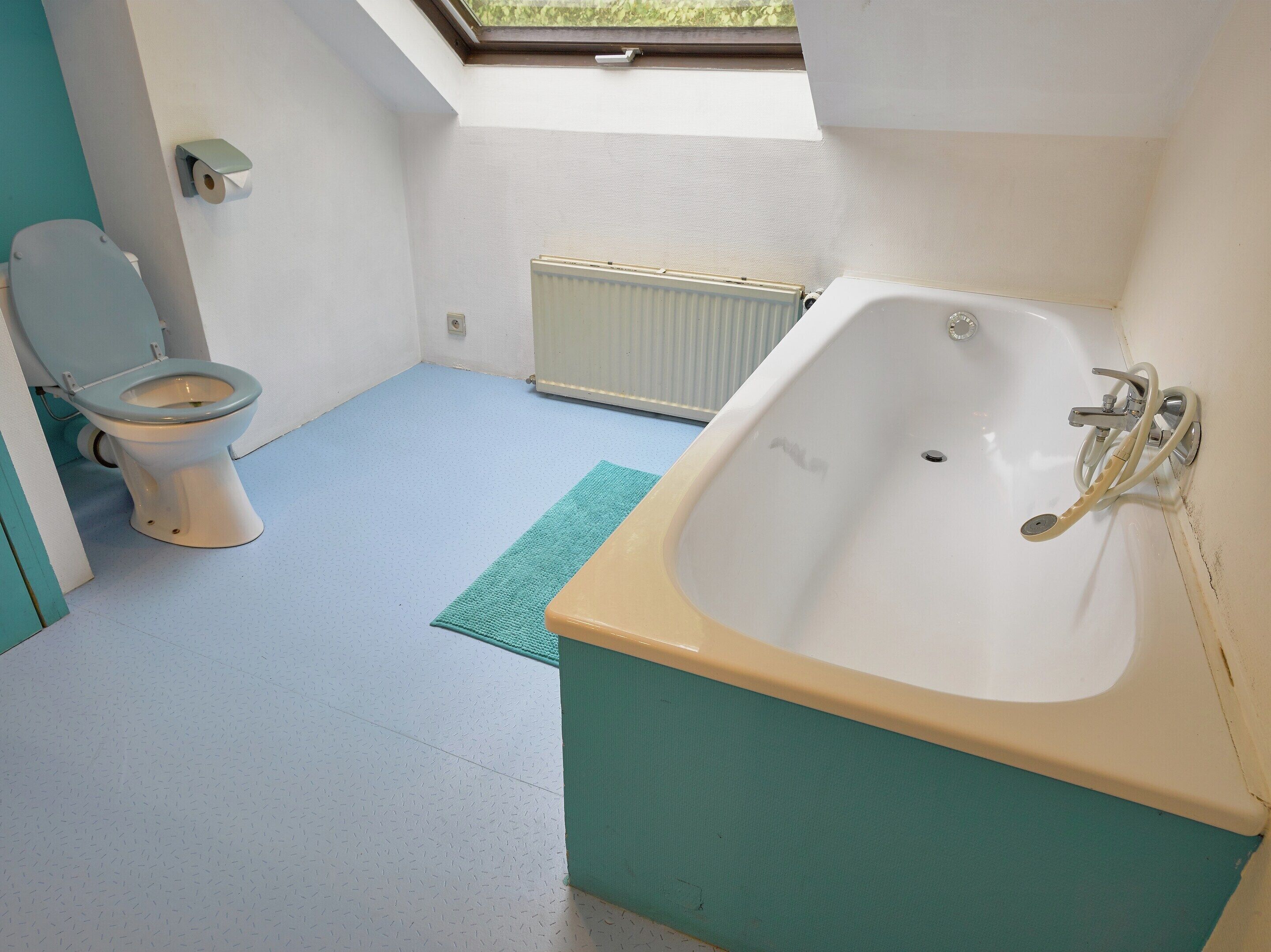 Une salle de bain équipée de toilettes, d’une baignoire et d’un radiateur.