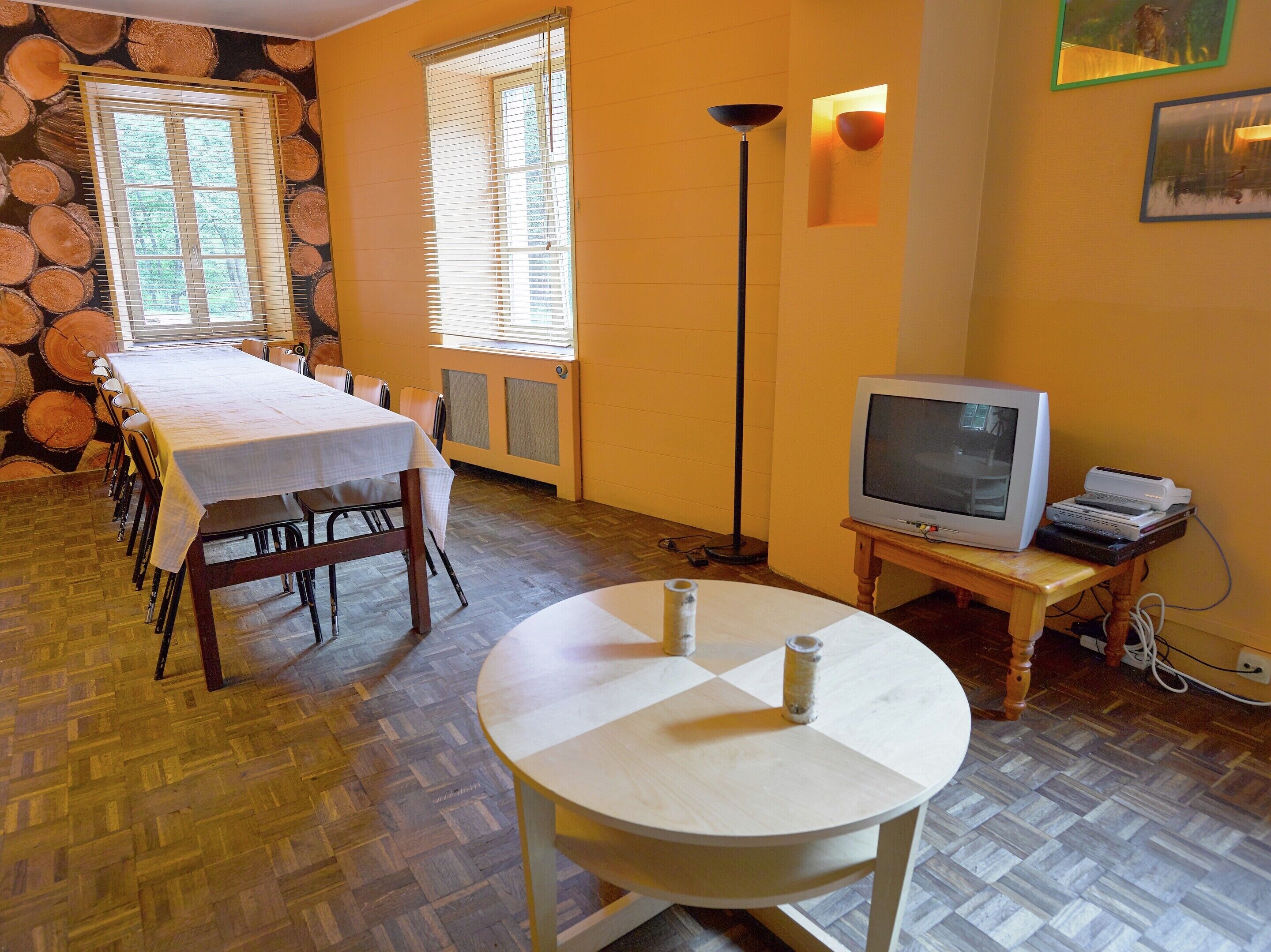 A dining area with a table set for four, a television on a stand, and a floor lamp.