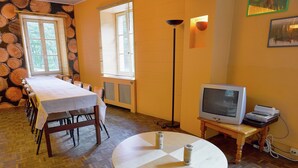 A dining area with a table set for four, a television on a stand, and a floor lamp. - Spacious Family Home, Sosoye (Anhée)