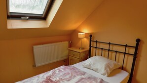 A bedroom with a bed, a nightstand, a lamp, a radiator, and a window. - Spacious Family Home, Sosoye (Anhée)