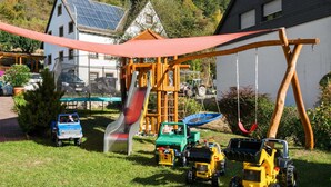 Un parque infantil con tobogán, columpios y vehículos de juguete.
