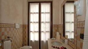 A bathroom with a checkered floor, a toilet, a sink with a mirror, and a hairdryer mounted on the wall. - Mansion in Nizza Monferrato With Pool & Views (Nizza Monferrato)