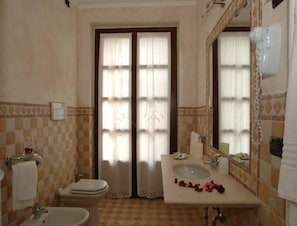 Un baño con piso a cuadros, un inodoro, un lavamanos con espejo y un secador de pelo montado en la pared.