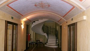 A grand hallway with a curved ceiling, a spiral staircase, and a small seating area with chairs and a table. - Mansion in Nizza Monferrato With Pool & Views (Nizza Monferrato)
