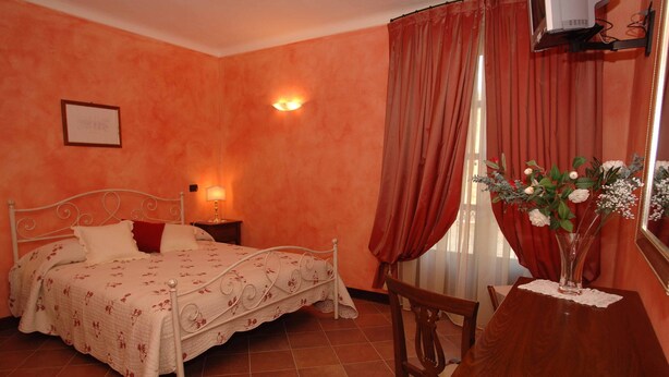 A bedroom with a bed, bedside table, lamp, and a dining table with chairs. - Mansion in Nizza Monferrato With Pool & Views (Nizza Monferrato)