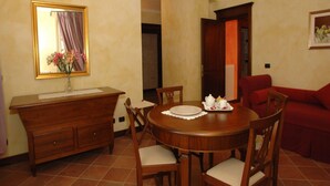 A dining area with a wooden table, chairs, a vase with flowers, and a mirror on the wall. - Mansion in Nizza Monferrato With Pool & Views (Nizza Monferrato)