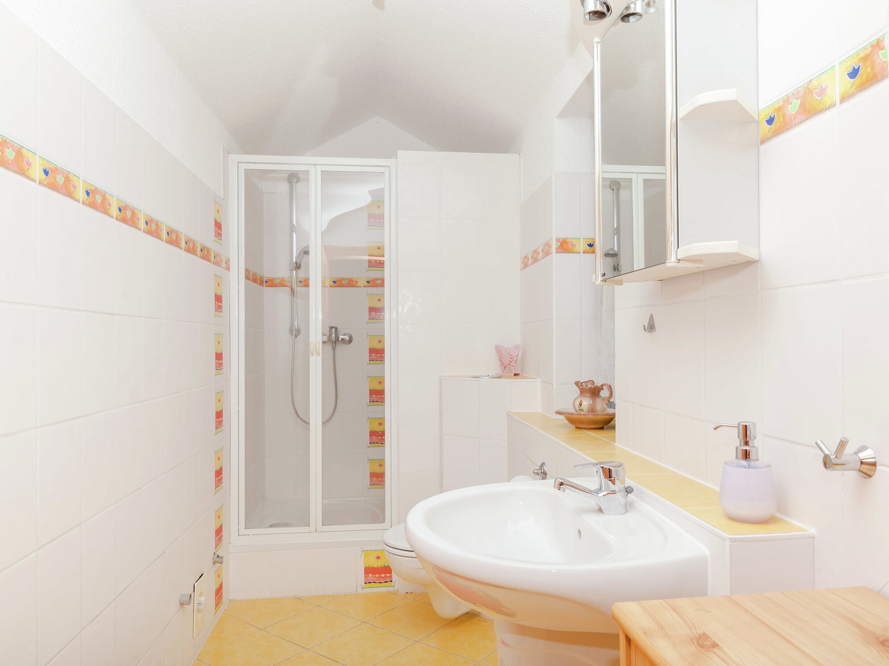 A bathroom with a shower, toilet, sink, and mirror.