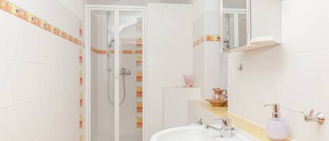 A bathroom with a shower, toilet, sink, and mirror.