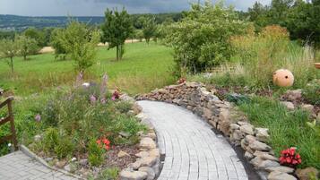 Un sendero curvo de ladrillo con borde de piedra, rodeado de exuberante vegetación y plantas en flor.