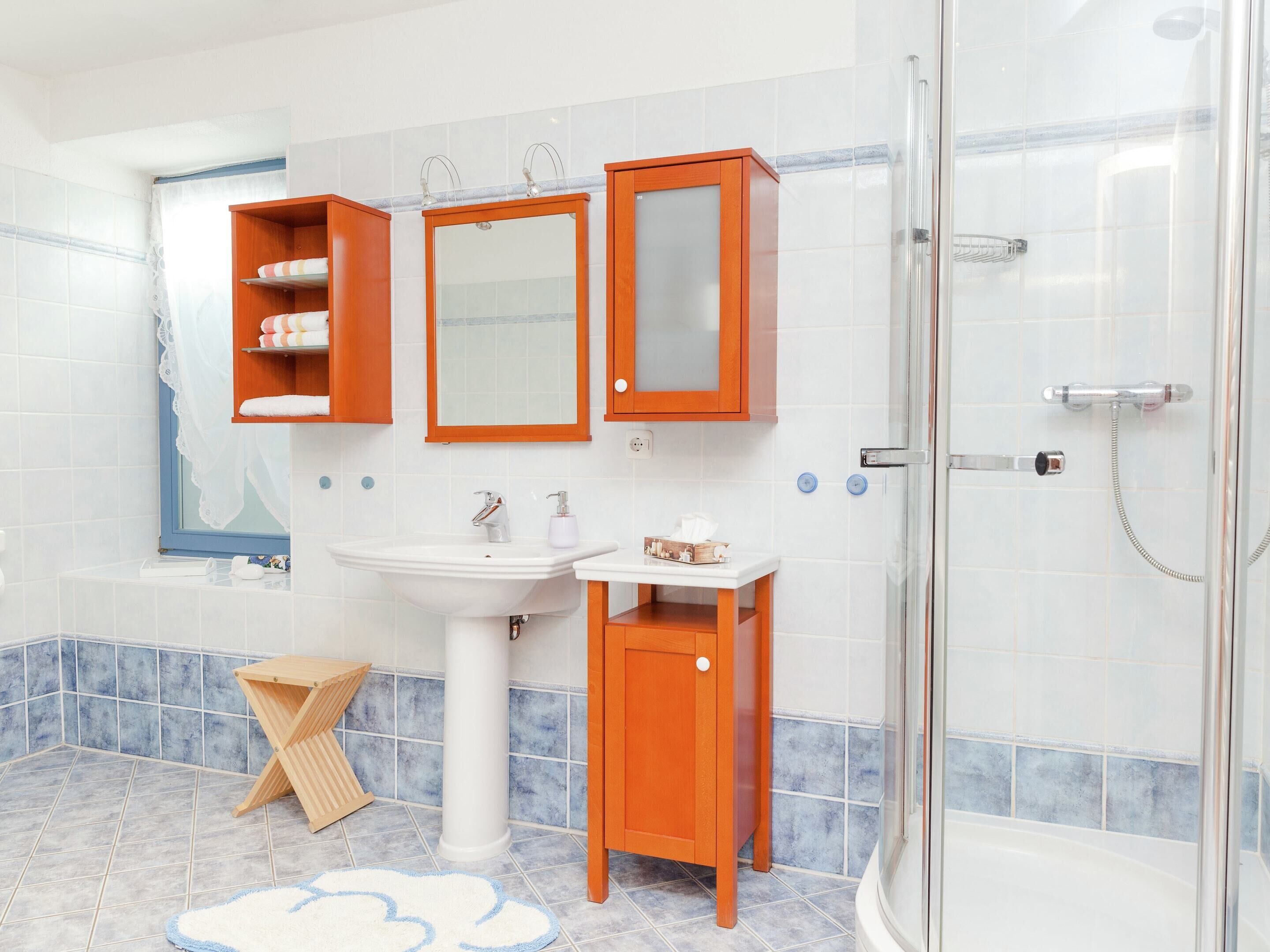 A bathroom with a bathtub, a sink, a shower, and wooden cabinets.