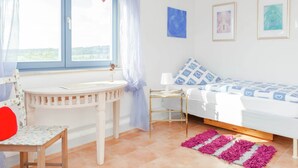 A bedroom with a bed, a bedside table, a chair, a window with curtains, and a view of the outdoors. - Villa mit Sauna und Garten (Schotten)