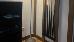 A corner room with a standing floor lamp, a TV stand, and a vertical rack with items.