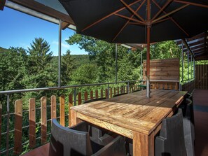 A wooden deck with a table and chairs, overlooking a forested area. - Modern Chalet in Sougne-remouchamps Near Forest (Aywaille)