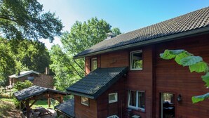 A wooden house with a sloped roof, a small porch, and a bench.