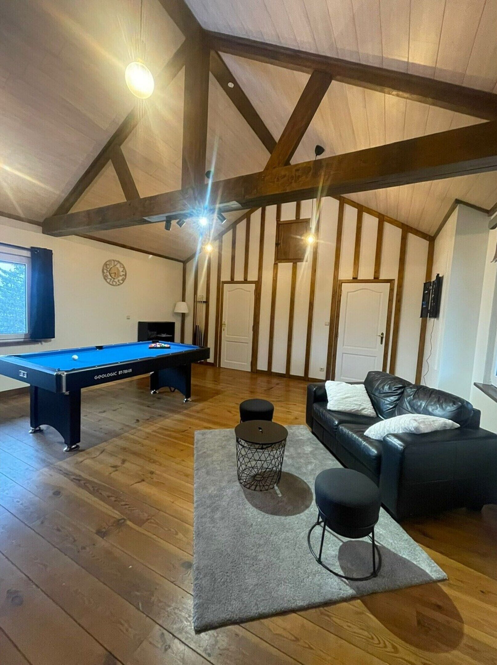 A room with a pool table, a sofa, and a small round table.