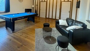 A room with a pool table, a sofa, and a small round table.