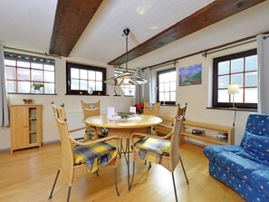 Un coin repas avec une table ronde, des chaises en osier et un canapé bleu.