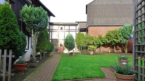 Un jardin avec un chemin en briques, des plantes en pot et une clôture en bois.