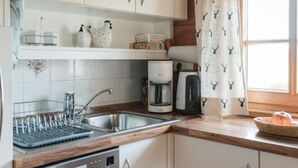 A kitchen with a dishwasher, coffee maker, and a window with curtains. - Holiday Home in Rattersberg Bavaria With Terrace (Viechtach)
