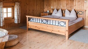A wooden bedroom with a bed, nightstands, and a window with curtains. - Holiday Home in Rattersberg Bavaria With Terrace (Viechtach)