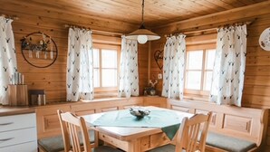 A cozy cabin-style room with a wooden interior, a dining table with four chairs, and curtains with a pattern of birds. - Holiday Home in Rattersberg Bavaria With Terrace (Viechtach)