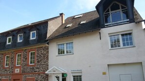 Un bâtiment doté d’une façade en pierre, d’une partie supérieure blanche et d’une porte de garage.