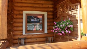 A wooden cabin with a window, a bench, and a hanging flower basket. - Comfort & Nature in Dankerode (Harzgerode)