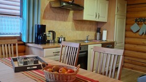A cozy kitchen with wooden cabinets, a coffee maker, and a dining area with a table set for two. - Comfort & Nature in Dankerode (Harzgerode)