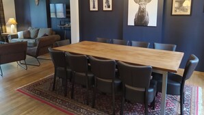 A modern dining area with a wooden table and chairs, a chandelier, and framed artwork on the walls. - Rustic Ardennes Retreat (Vielsalm)