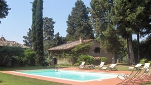 Une piscine rectangulaire bordée d’une terrasse carrelée, entourée d’une pelouse bien entretenue et de plusieurs chaises longues.