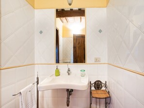 A bathroom with a white sink, a mirror, and a wooden door in the background. - Belvilla by OYO Pergolatico (San Casciano in Val di Pesa)