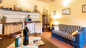 Un salon chaleureux avec un canapé et une table à manger, agrémentés d’une bouteille de vin, de verres et d’un menu.