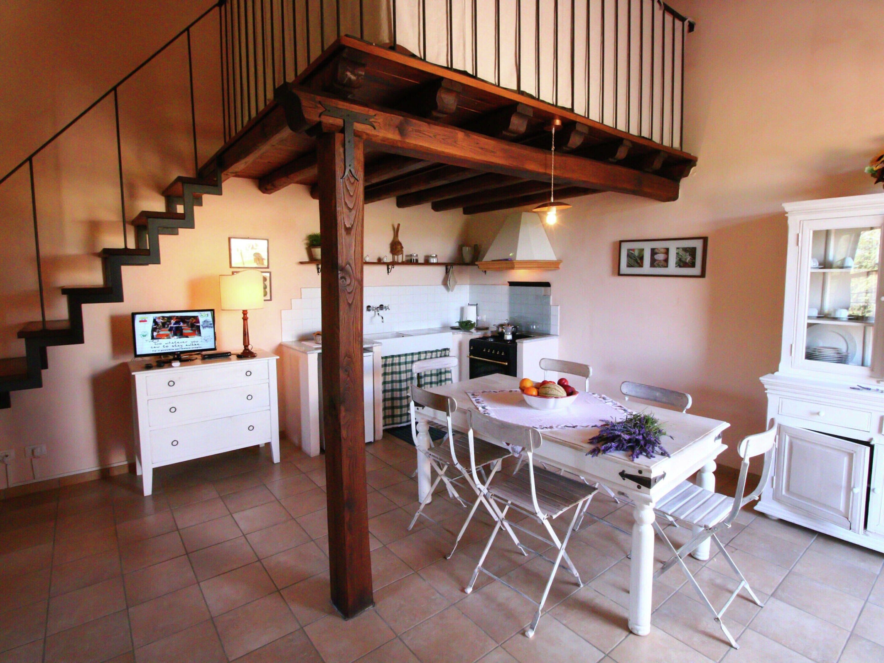 A kitchen with a dining table, chairs, a TV, and a staircase.