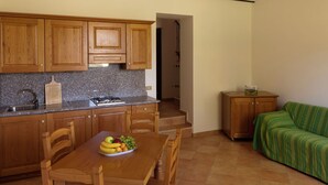 A compact kitchen with wooden cabinets, a granite countertop, and a dining table with chairs. - Belvilla by OYO Appartamento Yassine (Tredozio)