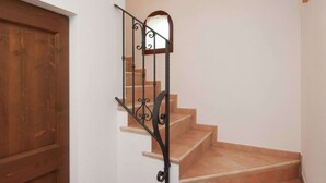 A wooden door, a staircase with a wrought iron railing, and a wall with a picture frame. - Belvilla by OYO Appartamento Yassine (Tredozio)