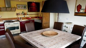 Een eetgedeelte met een houten tafel, stoelen en een grote zwarte lamp.