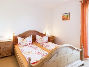 Cozy retreat with a double bed, nightstand, and lamp, set against a serene backdrop of a small painting.
